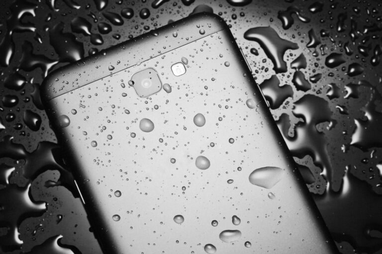 The back side of the smartphone with water drops on a black background with water drops. Protect your smartphone from water.